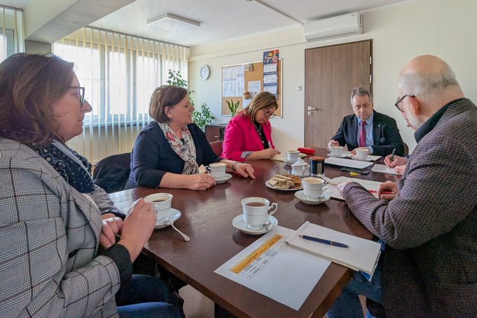Przy stole konferencyjnym w biurze siedzą od lewej trzy kobiety - przedstawicielki Kujawsko-Pomorskiego Oddziału PFRON, na środku mężczyzna, a po prawej stronie kolejny mężczyzna. Na stole leżą notesy i długopisy.