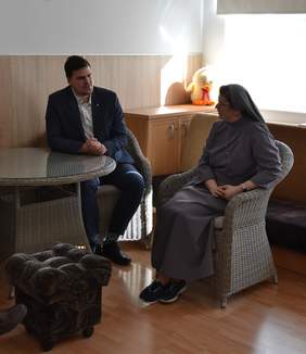 Pokaż zdjęcie: Na zdjęciu znajduje się kobieta i mężczyzna. Siedzą obok siebie na fotelach i prowadzą rozmowę