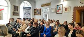 Pokaż zdjęcie: Konferencja, zdjęcie osób siedzących na krzesłach w ustawieniu kinowym. 