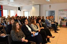 Pokaż zdjęcie: Zdjęcie uczestników konferencji siedzących na krzesełkach.