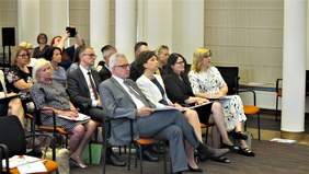 Pokaż zdjęcie: na krzesłach w rzędach siedzi publiczność konferencji