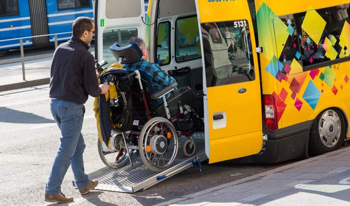 mężczyzna wwozi osobę na wózku do busa