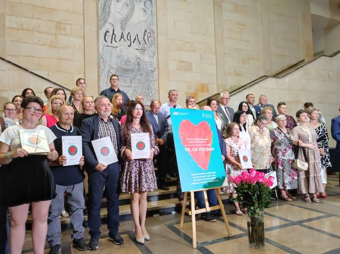 Zdjęcie grupowe tegorocznych laureatów. Laureaci stoją na schodach trzymając przed sobą otrzymane dyplomy.