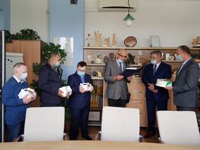 Sześciu mężczyzn, którzy stoją w szeregu, spotkali się. Trzech z nich trzyma w rękach białe opakowania z upominkami, jeden odczytuje list. Czuć że są skupieni nad słowami listu.