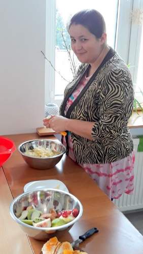 Pokaż zdjęcie: Kobieta krojąca owoce podczas zajęć ,,Rehabilitacja 25 plus" fot. ZSS w Biłgoraju"
