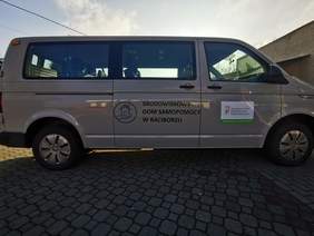 Pokaż zdjęcie: Na wypuzlowanym parkingu stoi duży biały bus na boku pojazdu widać logo i napis Środowiskowy Dom Samopomocy w Raciborzu oraz logo i napis dofinansowano ze środków PFRON
