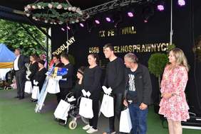 Pokaż zdjęcie: Uczestnicy Festiwalu w Podolanach - scena, na niej stoi grupa występujących artystów