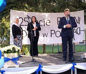Pokaż zdjęcie: Przewodniczący na scenie wita gości - za nim napis 25-lecie PSONI