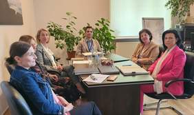Pokaż zdjęcie: Przy stole konferencyjnym siedzą kobiety i mężczyzna. Na stole leży dokumentacja programowa.