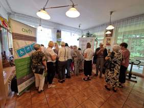 Pokaż zdjęcie: Seniorzy oglądają materiały informacyjne oraz sprzęty na stoisku PFRON i OWiT