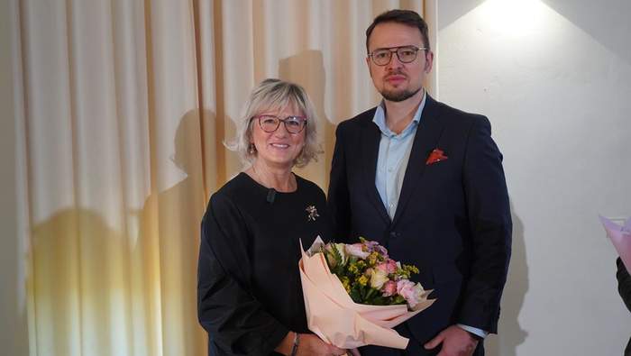 Kobieta i mężczyzna pozują do zdjęcia z bukietem kwiatów podczas uroczystości jubileuszowej 25-lecia projektu wiejskiego w Juchowie.
