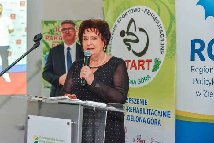 Pokaż zdjęcie: Danuta Tarnawska na tle baneru "Start" Zielona Góra z mikrofonem w ręku