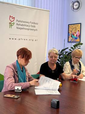 Pokaż zdjęcie: Przy stole konferencyjnym trzy kobiety w średnim wieku podpisują umowy.
