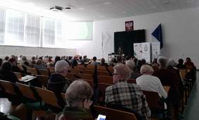 Pokaż zdjęcie: Zdjęcie sali konferencyjnej w kierunku prelegentki. 