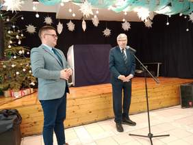 Pokaż zdjęcie: Na scenie stoi dyrektor Łódzkiego Oddziału PFRON, który przemawia do mikrofonu. Obok niego stoi starosta powiatu brzezińskiego. 