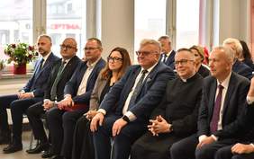 Pokaż zdjęcie: Zdjęcie zaproszonych gości siedzących na krzesłach, widok na pierwszy rząd.