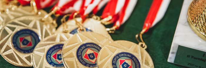 Pokaż zdjęcie: Koło siebie leży kilka złotych medalami z opaskami biało-czerownymi.