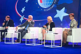 Scena, na niej na krzesłach siedzą paneliści