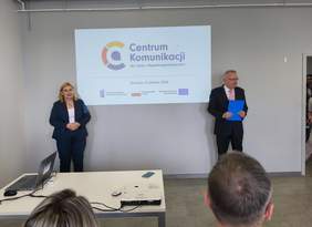 Oficjalne spotkanie w sali konferencyjnej na tle ekranu projekcyjnego z logo i napisem "Centrum Komunikacji dla Osób z Niepełnosprawnościami, Szczecin 9 czerwca 2026". Po lewej kobieta z w ciemnym garniturze ze złożonymi przed sobą rękoma. Po prawej mężczyzna w garniturze i okularach. 