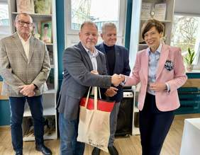 Pokaż zdjęcie: W centrum stoją dwie osoby: Michał Pawlak – kierownik placówki oraz Anna Skupień – dyrektor Oddziału Wielkopolskiego PFRON, którzy podają sobie ręce. Z tyłu stoi dwóch mężczyzn – przedstawicieli zarządu Fundacji „Miłosierdzie”.