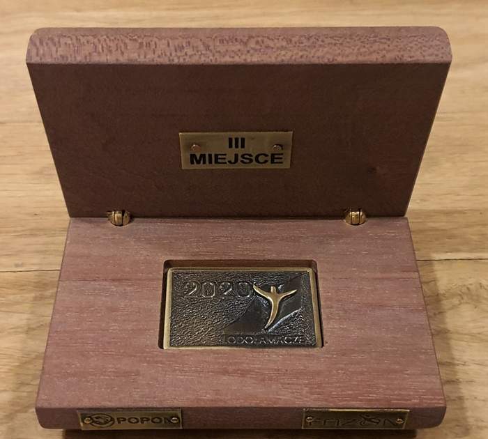 Pokaż zdjęcie: Na zdjęciu nagroda, którą otrzymała Fundacja L’Arche, Śledziejowice w Wieliczce - brązowy medal w drewnianym opakowaniu