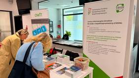 Pokaż zdjęcie: Dwie kobiety oglądają materiały informacyjne na stoisku PFRON
