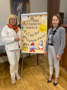 Pokaż zdjęcie: Dyrektor Marta Mordarska oraz prezes Stowarzyszenia "Nadzieja" - Teresa Jaros-Ligaszewska. Pomiędzy uśmiechniętymi kobietami na sztaludze ustawiony jest  plakat z nazwą Festiwalu