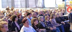 Pokaż zdjęcie: W sali siedzi tłum ludzi. Jest to widownia festiwalu Albertiana. Wszyscy patrzą w kierunku sceny. 