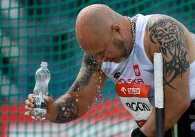 Pokaż zdjęcie: Mężczyzna w sportowym stroju, który polewa się butelką wody. 