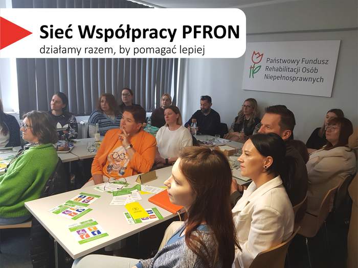 Pokaż zdjęcie: Grupa kilkunastu osób siedzących przy stole konferencyjnym w kształcie liter „U”, na których leżą kolorowe broszury, notesy oraz napoje. Przy stołach siedzi kilkanaście osób. Na prawej ścianie wisi prostokątna tablica z logo w kształcie tulipana i napisem: „Państwowy Fundusz Rehabilitacji Osób Niepełnosprawnych”. W lewym górnym rogu widnieje hasło „Sieć Współpracy PFRON – działamy razem, by pomagać lepiej”.