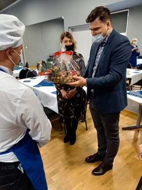 Pokaż zdjęcie: Dyrektor Oddziału PFRON ogląda świąteczny stroik wykonany z naturalnych produktów.  