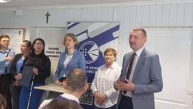 Pokaż zdjęcie: W jednym z pomieszczeń placówki, trwa uroczyste otwarcie, goście gratulują otwarcia. Na zdjęciu zarząd placówki i goście stoją w jednym rzędzie.