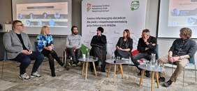 Pokaż zdjęcie: Paneliści kobiety i mężczyźni siedzą na środku sali na krzesłach. Dyskusję moderuje kobieta. Wśród panelistów są osoby z niepełnosprawnościami.