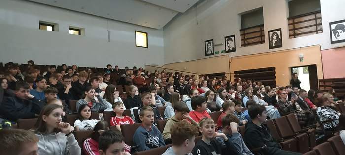 Pokaż zdjęcie: Wypełniona sala przez uczniów, którzy siedzą na fotelach w auli