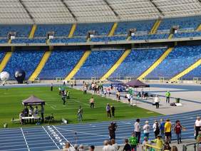 Pokaż zdjęcie: trzech zawodników gra na trawiastej płycie stadionu w bule tradycyjną francuską grę towarzyską