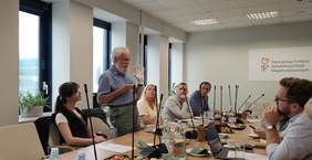 Pokaż zdjęcie: Ekspert z Ośrodka Wsparcia i Testów w Laskach w Laskach pokazujący sposób na komunikację pozawerbalną z wykorzystaniem rękawiczki z literami.