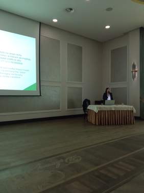 Pokaż zdjęcie: Prelegent kobieta podczas wykładu w sali konferencyjnej.
