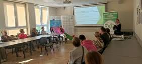 Pokaż zdjęcie: Widoczny pracownik CIDON opowiadający o wyświetlonej prezentacji, a także goście spotkania