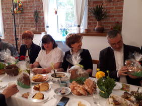 Świąteczny stół z potrawami, za nim uśmiechnięte osoby.