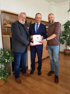 trzech mężczyzn stoi, pozują do zdjęcia trzymają wspólnie dokumenty