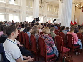 Widok licznie zebranych uczestników wydarzenia, jasna, przestronna sala