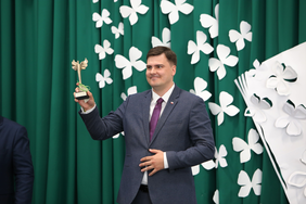 Pokaż zdjęcie: Dyrektor PFRON trzyma w ręku statuetkę – prostego złotego anioła z rozłożonymi skrzydłami. Na dole statuetki jest wygrawerowane: Przyjaciel Szkoły Mateusz Szkaradziński  ZPSW w Iławie 2022.    