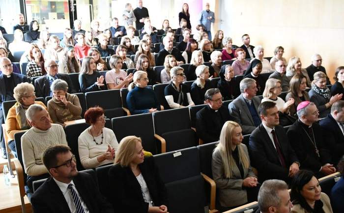 Pokaż zdjęcie: Uczestniczy konferencji siedzą w fotelach w auli, na przodzie Dyrektor Oddzialu Lubuskiego PFRON