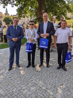 Trzech mężczyszn i chłopiec pozują do zdjęcia, stoją pod drzewem