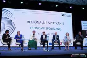 Pokaż zdjęcie: Na cenie na fotelach siedzi 6 osób, w tle zdjęcie z prezentacji, osoby te biorą udział w panelu dyskusyjnym.