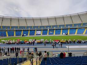 Pokaż zdjęcie: Wszystkie drużyny UTW uczestniczące w olimpiadzie stoją wzdłuż płyty boiska