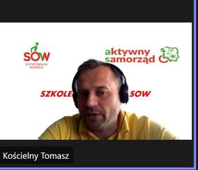 Pokaż zdjęcie: Mężczyzna w żółtej koszulce i słuchawkach za nim białe tło z logo Aktywnego Samorządu i Systemu Obsługi Wsparcia