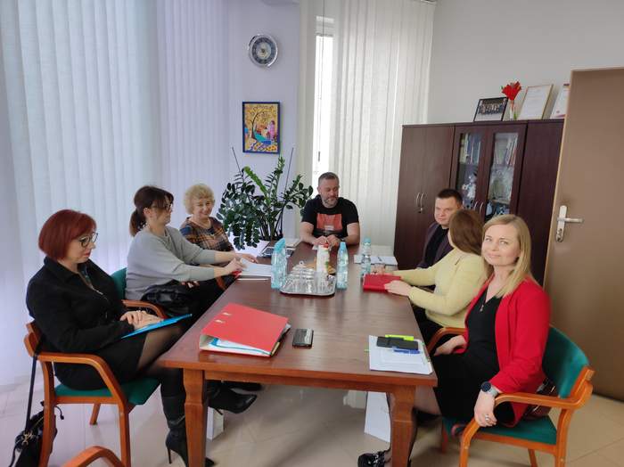 Pokaż zdjęcie: Przy stole siedzi mieszana grupa siedmiu osób, trwają konsultacje