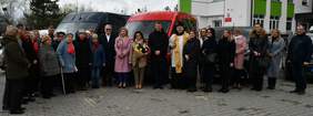 Pokaż zdjęcie: Na tle czerwonego busa pozuje duża grupa osób ustawiona w półkole.