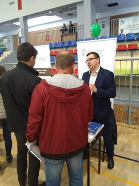 Pokaż zdjęcie: Pracownik PFRON udziela informacji zainteresowanym na targach pracy w Zagnańsku